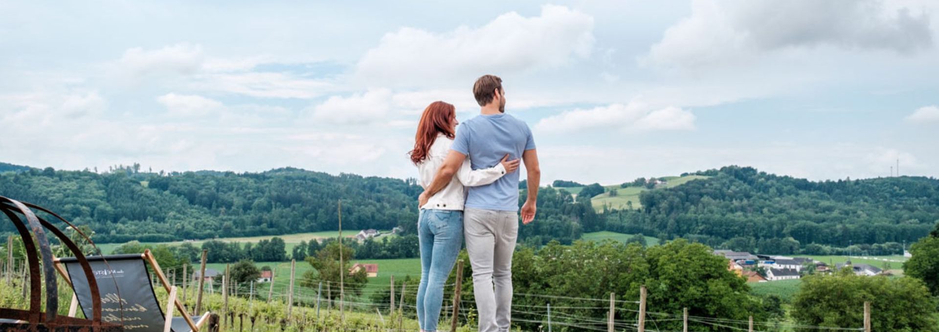 Paar steht mit dem Rücken zur Kamera und blickt über die Weingärten
