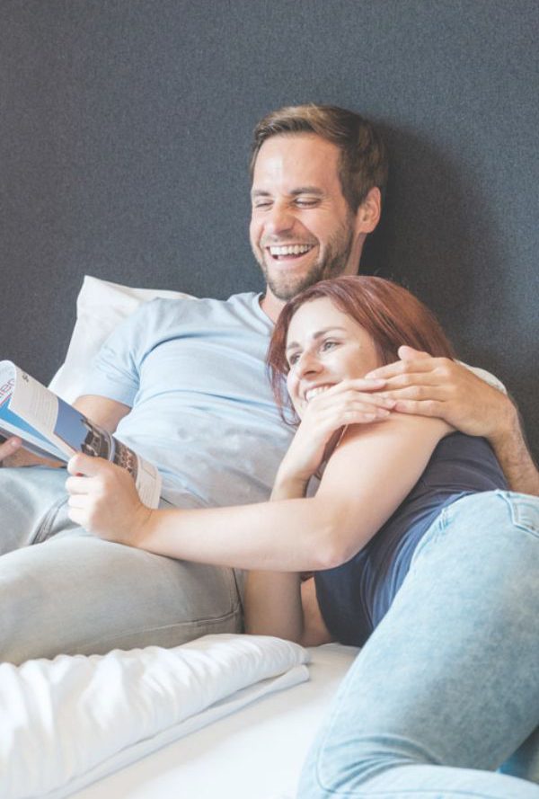 Paar liegt im Bett und blättert eine Zeitschrift